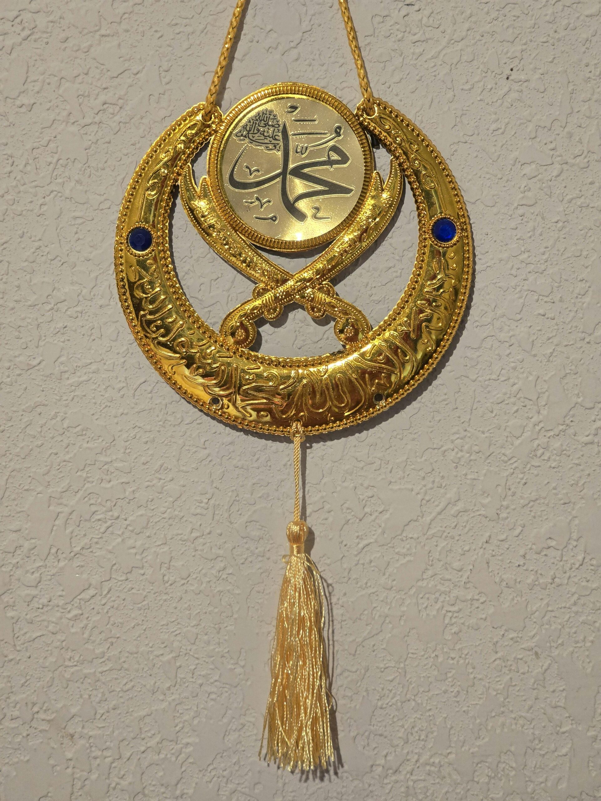 Intricate gold Islamic decor with calligraphy on textured wall, featuring detailed craftsmanship.